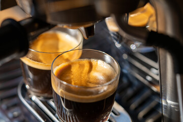 Closeup of two glasses of freshly brewed espresso coffee with crema made by an espresso machine