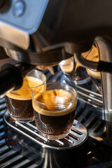 Two glasses of freshly brewed espresso coffee with crema made by an espresso machine