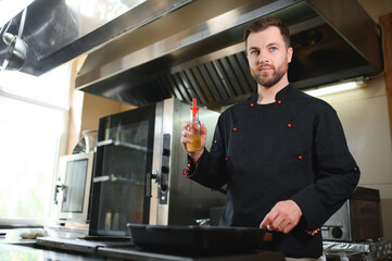 Portrait of handsome positive chef cook at the restaurant kitchen