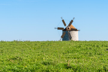 Rustic stone windmill in a grassy field
