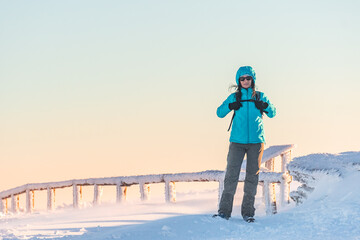 Hruby Jesenik, Young woman hiking on mountain snowy trail, walking on white snow through snowy peak, winter landscape in mountains on sunny day.