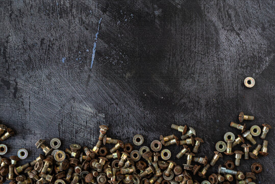Top Down Aerial View of Rusty Bolts and Washers on a Textured Dark Surface with Empty Space for Text or Content &ndash; Industrial Hardware Background