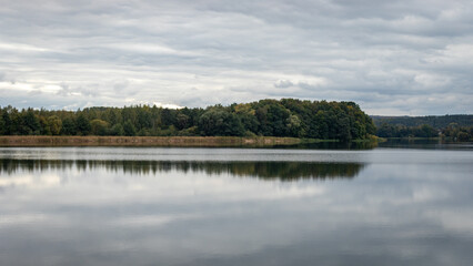 Fototapeta premium Peaceful lake with forest reflections under cloudy sky