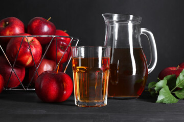 Tasty fresh apple juice and fruits on black wooden table