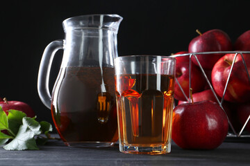Tasty fresh apple juice and fruits on black wooden table