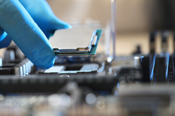 Man installing computer chip onto motherboard at table, closeup