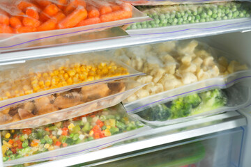 Plastic bags with different frozen vegetables in refrigerator, closeup