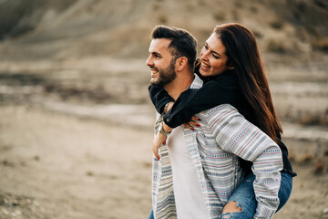 Happy couple piggybacking during road trip in desert