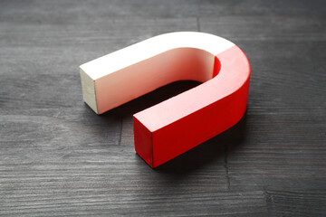 One horseshoe magnet on black wooden table, closeup