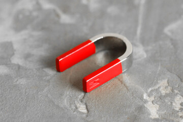 One horseshoe magnet on grey textured table, closeup