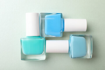 Set of different nail polishes in bottles on turquoise background, flat lay