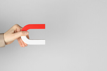 Woman with horseshoe magnet on grey background, closeup. Space for text