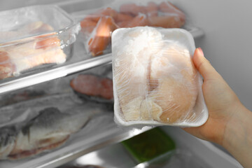 Woman taking frozen chicken breasts out of fridge, closeup
