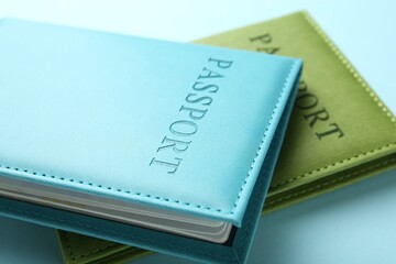Passports in color covers on light blue background, closeup