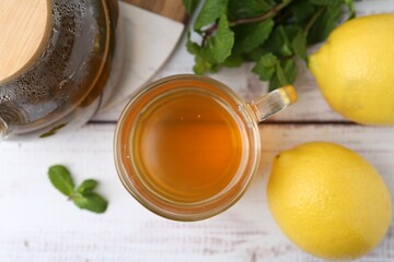 Aromatic mint tea with lemons and fresh leaves on white wooden table, flat lay