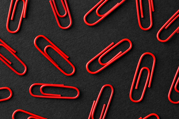 Red paper clips on black background, flat lay