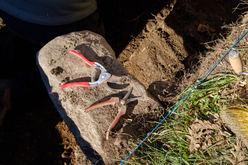 tools, trowel, pruning shears and broom in an archaeological dig