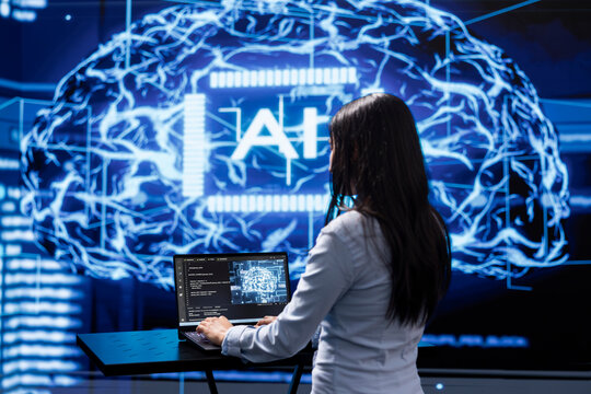 Programmer analyzing complex AI brain models on laptop, running simulations. Female employee using machine learning software on notebook device to develop artificial intelligence technology - Powered by Adobe