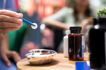 Medical assistant preparing daily dose of pills and vitamins for elderly patients, dividing the medicaments in separate bottles for effectiveness. Nurse giving medical drugs to people. Close up.