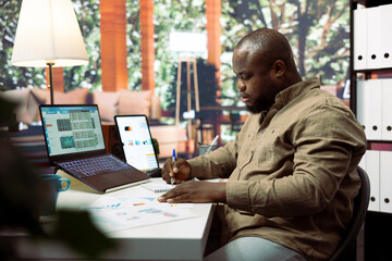 General manager creating financial reports plan with documents at his home office, examining annual data infographics. Entrepreneur review performance metrics and economic statistics.