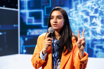 Specialist talking in mic at technology summit, explaining impact of AI technology on world....