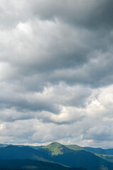 Scenic landscape showcasing a mountain range beneath a dramatic overcast sky. The contrast between...
