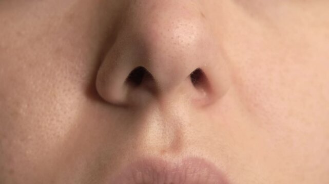  A close-up video of a woman's nose as she moves her nasal muscles. Captured in high detail, showcasing subtle movements and skin texture