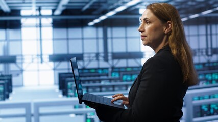 Computer scientist doing yearly maintenance using laptop to prolong data center equipment life...