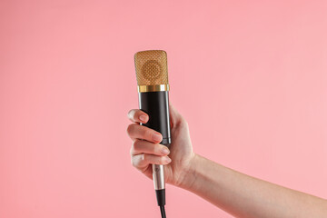 Woman with microphone on pink background, closeup