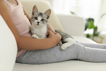 Little girl with cute kitten at home, closeup