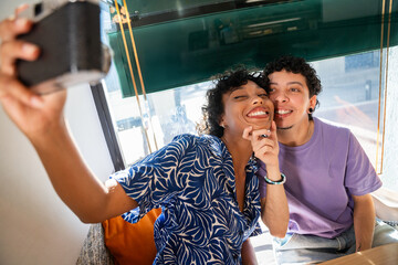 Happy LGBTQ+ couple taking a selfie in a cozy cafe setting