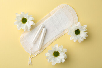 Menstrual pad, flowers and tampons on beige background, flat lay