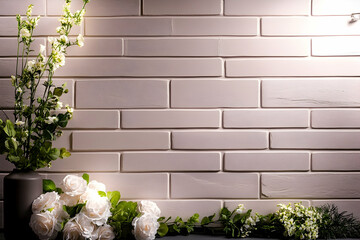 Naklejka premium White roses and flowers against a white brick wall background. Ideal for greeting cards or website banners