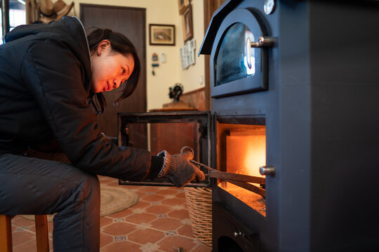 Asian woman managing fire in a wood burning stove