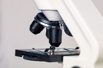 Science. Microscope with glass slide on light grey background, closeup