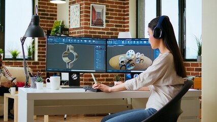Asian professional engineer works on coding industrial designs using advanced software tools. Living room office includes dual monitors and technical equipment for high productivity. Camera A.