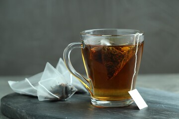 Tea bag in glass cup with hot drink on gray table