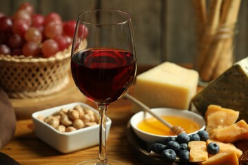 Red wine and different snacks served on table, closeup