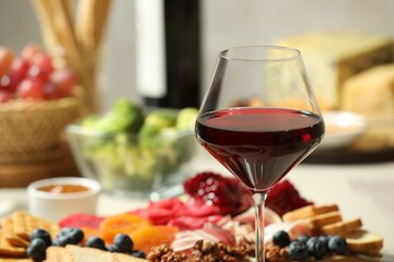 Red wine and different snacks served on table, closeup