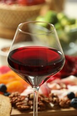 Red wine and different snacks served on table, closeup