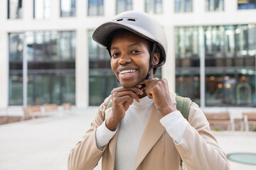 Urban black woman smiling while adjusting her helmet strap