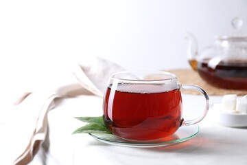 Refreshing black tea in cup on light table. Space for text