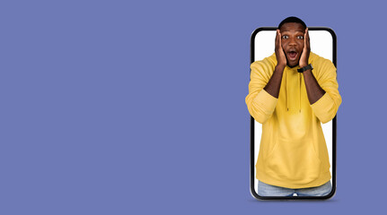A person in a yellow hoodie shows surprise and joy while using a smartphone with a large screen. The background is a solid color, emphasizing the expression of excitement and the technology in hand.