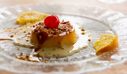 Popular Andalusian dessert tocino de cielo baked from egg yolks with sugar syrup served with caramel sauce, nuts and slices of orange..
