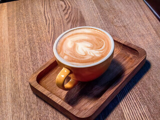 A cup of hot coffee sits on the table in a wooden tray.