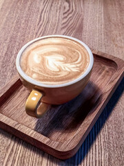 A cup of hot coffee sits on the table in a wooden tray.