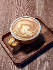 A cup of hot coffee sits on the table in a wooden tray.