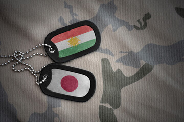 vintage army blank, dog tag with flag of kurdistan and japan on the khaki texture background....