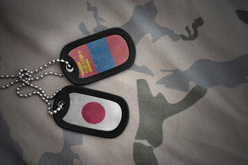 vintage army blank, dog tag with flag of mongolia and japan on the khaki texture background....