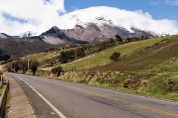 CARRETERA JUNTO A CAMPOS Y FRENTE AL VOLCAN CHIMBORAZO EN UN DÍA SOLEADO CON NUBES EN ECUADOR